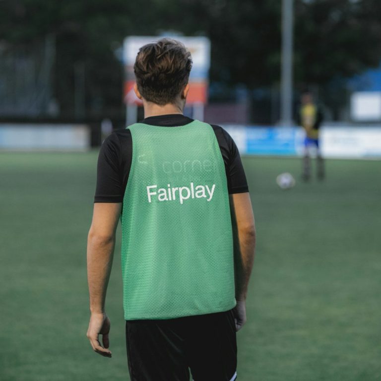 Spieler in grünem Trikot mit der Aufschrift "Fairplay" auf dem Fußballfeld.